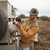 Model wearing a Poncho The Ditch Chicken, petting a dog in the back of a truck