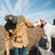 Model wearing a Poncho The Ditch Chicken, petting a dog in the back of a truck