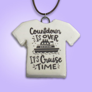A handmade ceramic Tshirt pendant with the words "Countdown is Over Its Cruise Time". With a purple background. A handmade ceramic Tshirt pendant with the words "Countdown is Over Its Cruise Time". With a purple background.