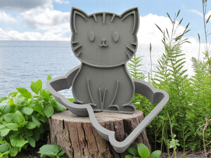 A cute cat shaped pottery stamp with cutter. Shown with plants, ocean & clouds look background. A cute cat shaped pottery stamp with cutter. Shown with plants, ocean & clouds look background.