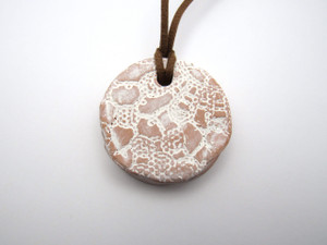 A handmade round terracotta white lace aromatherapy ceramic pendant necklace. With a brown cord necklace. A handmade round terracotta white lace aromatherapy ceramic pendant necklace. With a brown cord necklace.