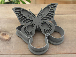 A Beautiful Butterfly shaped clay pottery stamp with cutter. With the stamp tilted up on cutter. With a wood table look background.