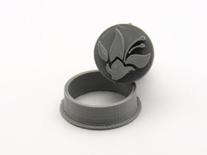 An abstract flower with stamen round pendant clay stamp with cutter. The stamp is tilted against the cutter. An abstract flower with stamen round pendant clay stamp with cutter. The stamp is tilted against the cutter.
