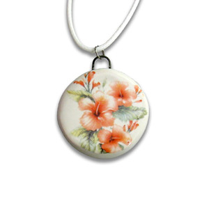 A handmade round peach hibiscus flowers and leaves ceramic pendant necklace. On a white cord necklace. A handmade round peach hibiscus flowers and leaves ceramic pendant necklace. On a white cord necklace.