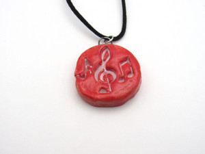 A handmade ceramic round pendant music notes in solid red necklace. On a black cord necklace. A handmade ceramic round pendant music notes in solid red necklace. On a black cord necklace.