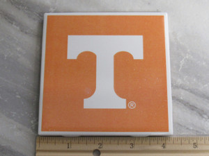 A UT Vols White Power T on an orange Ceramic Coaster Hot Pad Trivet. With ruler. Measuring approximately 4 inches wide. A UT Vols White Power T on an orange Ceramic Coaster Hot Pad Trivet. With ruler. Measuring approximately 4 inches wide.