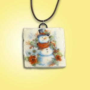A handmade snowman with black Top Hat ceramic necklace. With a yellow background. A handmade snowman with black Top Hat ceramic necklace. With a yellow background.