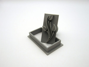 A stems with leaves (Design 1) rectangle pendant clay pottery stamp tilted on top of the rectangle cutter. A stems with leaves (Design 1) rectangle pendant clay pottery stamp tilted on top of the rectangle cutter.