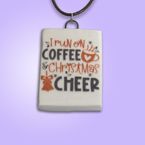Fun Christmas Handmade Ceramic Necklace with the words "I run on Coffee and Christmas Cheer". With a purple background. Fun Christmas Handmade Ceramic Necklace with the words "I run on Coffee and Christmas Cheer". With a purple background.
