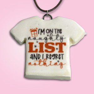 Fun Christmas Handmade ceramic Tshirt Shaped necklace with the words "I'm on The Naughty List and I regret Nothing." Black cord necklace. On a pink background. Fun Christmas Handmade ceramic Tshirt Shaped necklace with the words "I'm on The Naughty List and I regret Nothing." Black cord necklace. On a pink background.