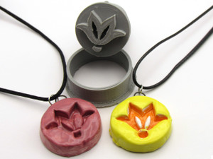 A handmade (Drawn Design 1) infusion square ceramic necklace. With a black cord necklace. Shown with two finished necklaces. One solid burgundy and orange flower with a yellow background pendant necklaces on black cord necklaces. A handmade (Drawn Design 1) infusion square ceramic necklace. With a black cord necklace. Shown with two finished necklaces. One solid burgundy and orange flower with a yellow background pendant necklaces on black cord necklaces.