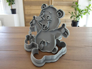 A cute bear shaped clay pottery stamp with cutter. Shown with stamp tilted on top of the cutter. With a table look background. A cute bear shaped clay pottery stamp with cutter. Shown with stamp tilted on top of the cutter. With a table look background.