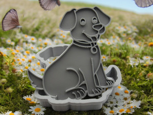 The front view of A Cute Puppy Dog Shaped Clay Cutter for handbuild slab pottery. Shown tilted on top of the cutter. Shown with a field with daisies and butterflies look background.
