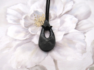 A black Handcrafted Teardrop Shaped Ceramic Pendant Necklace. On a black corded necklace. With a white floral look background. A black Handcrafted Teardrop Shaped Ceramic Pendant Necklace. On a black corded necklace. With a white floral look background.