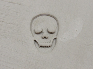 A clay imprint of a round Skull Stamp with Cutter. A clay imprint of a round skull stamp with cutter. A clay imprint of a round Skull Stamp with Cutter. A clay imprint of a round skull stamp with cutter.