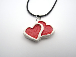 A Ceramic Double Red Hearts with White outline pendant necklace. On black corded necklace. A ceramic double red hearts with white outline pendant necklace. On black cord necklace. A Ceramic Double Red Hearts with White outline pendant necklace. On black corded necklace. A ceramic double red hearts with white outline pendant necklace. On black cord necklace.