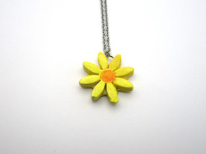 A Small Daisy Shaped Flower Ceramic Pendant Necklace. With yellow petals and an orange center. On a silver colored chain necklace. A Small Daisy Shaped Flower Ceramic Pendant Necklace. With yellow petals and an orange center. On a silver colored chain necklace.