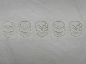 A clay imprint of a Jumbo Scary Skull border clay stamp for ceramic pottery. A clay imprint of a Jumbo Scary Skull border clay stamp for ceramic pottery.