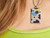 A handmade rectangle ceramic fun celebration pendant necklace on a yellow cord necklace. Shown on a woman's neck.