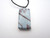 A rectangle infusion abstract (Design 3) blue with brown pattern ceramic pendant necklace. On a black cord necklace.