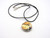 A ceramic round abstract pendant necklace, featuring fall colors. On a black cord necklace.