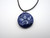A handmade navy abstract 3 point design ceramic pendant necklace. On a black cord.