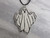 A handmade ceramic ghost statement pendant necklace. On a black cord necklace. On a gray marble look background. A handmade ceramic ghost statement pendant necklace. On a black cord necklace. On a gray marble look background.