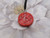 A handmade ceramic round pendant music notes in solid red necklace. On a black cord necklace. With a white floral look background.