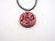 A handmade ceramic round pendant music notes in solid burgundy necklace. On a black cord necklace.