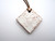 An aromatherapy terracotta diamond shaped white lace ceramic handmade necklace. On a brown cord necklace. An aromatherapy terracotta diamond shaped white lace ceramic handmade necklace. On a brown cord necklace.