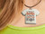 A Handmade Christmas "Dear Santa I'm Sorry for What I Said" Ceramic Tshirt Pendant. With a black cord necklace. Shown on a woman's neck. A Handmade Christmas "Dear Santa I'm Sorry for What I Said" Ceramic Tshirt Pendant. With a black cord necklace. Shown on a woman's neck.