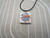 A Patriotic red and blue flowers with Flag Square Pendant (V1) Infusion pendant necklace. On a black cord necklace. With a beige and white background.
