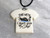 A handmade ceramic Tshirt necklace with the words "This week I don't Give a Ship. on a black cord necklace. With a gray marble look background.