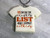 Fun Christmas Handmade ceramic Tshirt Shaped necklace with the words "I'm on The Naughty List and I regret Nothing." Black cord necklace. On a gray marble look background.