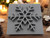 A Snowflake Mug Clay Stamp for handbuild pottery V1. With tea lights and pine cones on a wood table look background.