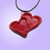 A handmade red double heart ceramic pendant necklace. On a black cord necklace. With a purple background. Perfect for a Valentine's day gift. Romantic sweetheart gift.