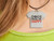 A Handmade Ceramic Tshirt Necklace saying "Dogs Make Me Happy". Shown on woman's neck. A Handmade ceramic Tshirt necklace saying Dogs make Me Happy". Shown on a woman's neck. A Handmade Ceramic Tshirt Necklace saying "Dogs Make Me Happy". Shown on woman's neck. A Handmade ceramic Tshirt necklace saying Dogs make Me Happy". Shown on a woman's neck.