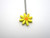 A Small Daisy Shaped Flower Ceramic Pendant Necklace. With yellow petals and an orange center. On a silver colored chain necklace.