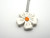 A 5 Petal shaped Ceramic Flower handcrafted necklace. With white petals and an orange center. On a silver colored chain necklace. A 5 Petal shaped Ceramic Flower handcrafted necklace. With white petals and an orange center. On a silver colored chain necklace.
