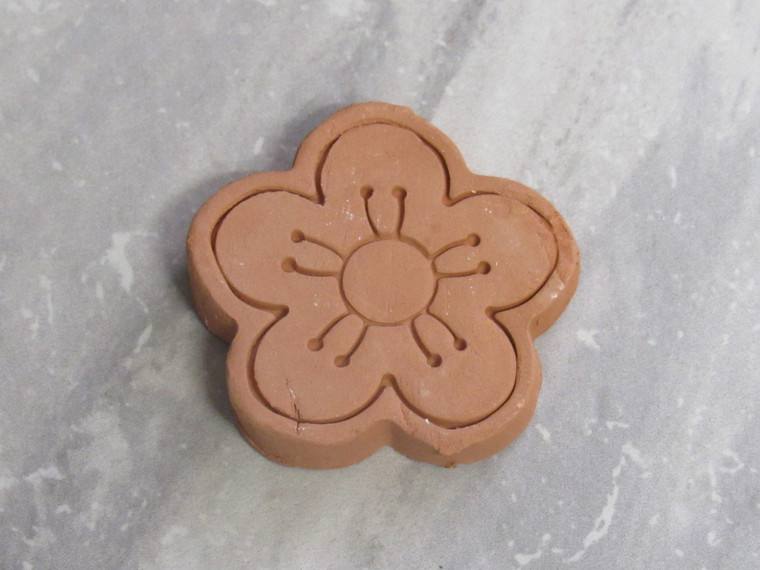 A finished brown terracotta clay sugar saver- small flower bloom. On a gray marble look background.