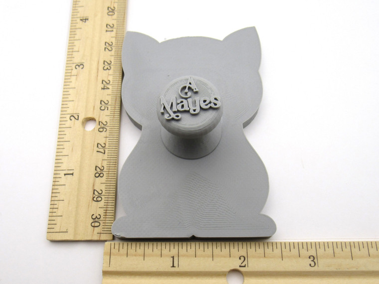 A cute cat shaped pottery stamp with cutter. Next to ruler. Measuring approximately 2 inches by 3 inches.