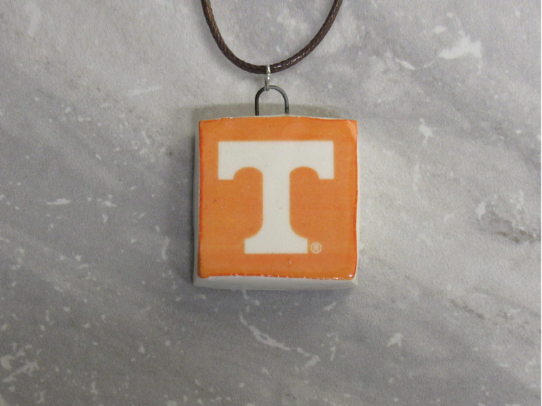 A TN Vols Orange with White Power T square ceramic necklace. On a gray marble look background.