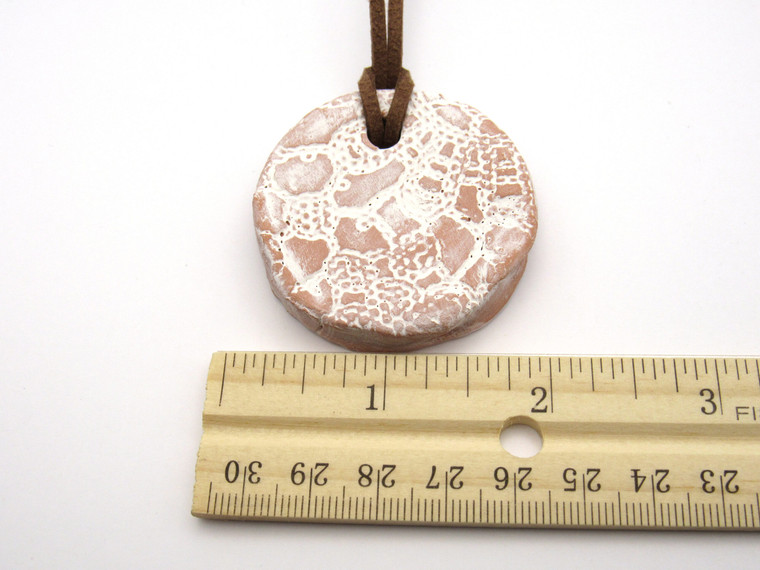 A handmade round terracotta white lace aromatherapy ceramic pendant necklace. With ruler.