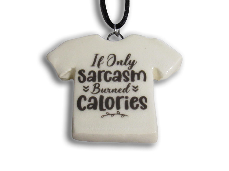 A handmade ceramic Tshirt pendant with the words "If Only Sarcasm Burned calories". On a black cord necklace.