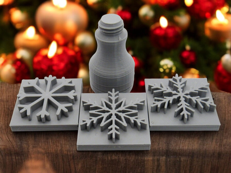 A set of 3 Snowflake Clay Pottery Stamps with 1 Interchangeable handle. On a table with Christmas tree look background.