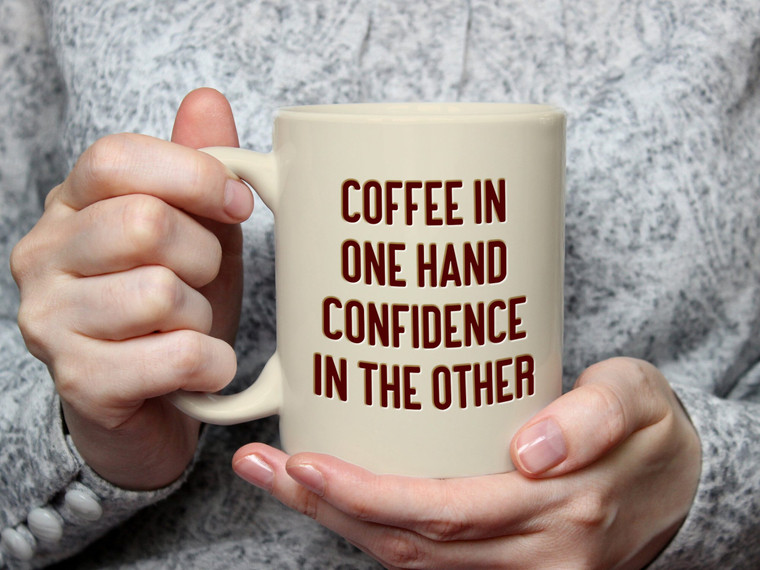 A mug with the words "Coffee in One Hand Confidence in the other".