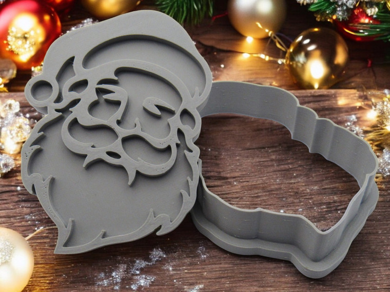 A Traditional Santa Shaped Pottery Stamp with Clay cutter. On a table look with a Christmas Tree in the background.