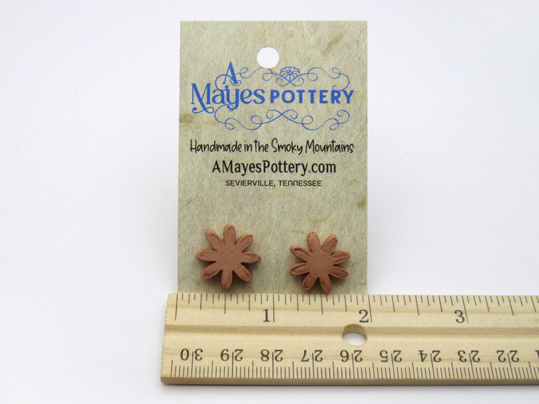 A set of small flower aromatherapy terracotta post earrings. On an A Mayes Pottery card.   With a ruler.