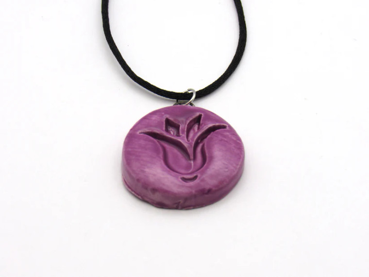 An handmade purple tulip ceramic pendant necklace. On a black cord necklace.