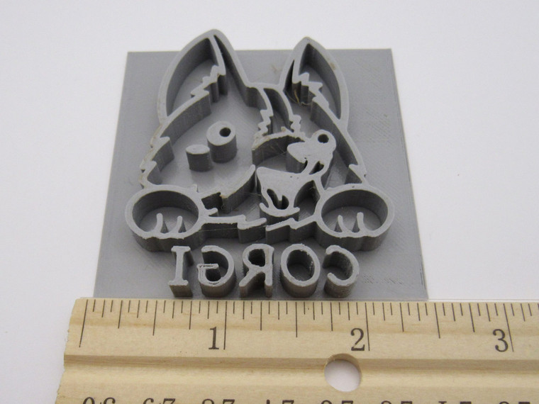 A Corgi Dog Clay Mug Stamp for handbuild pottery. With ruler. Showing 2.5 inches wide.